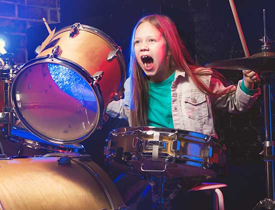 Child drummer playing drums in the heated home garage in comfort.